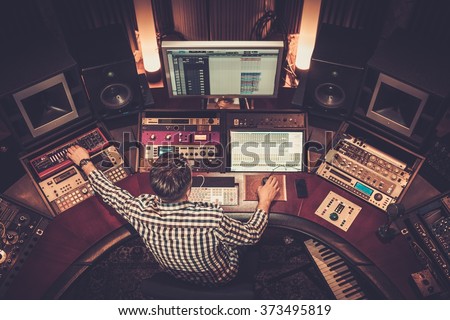 Sound engineer working at mixing panel in the boutique recording studio. Royalty-Free Stock Photo #373495819