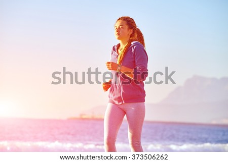 young woman running on the beach against sea and blue sky at early morning 