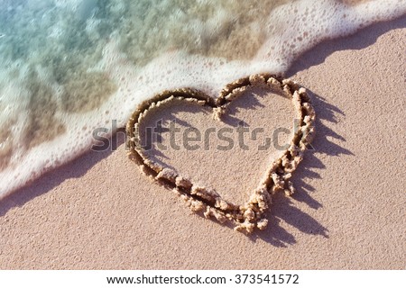 heart on a sand of beach with wave on background
