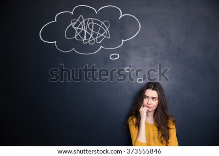 Frowning thougthful young woman thinking about problems over blackboard background
