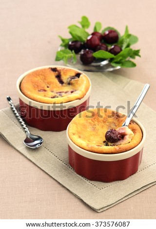 small Clafoutis with cherries and mint in a ceramic molds on a napkin from flax