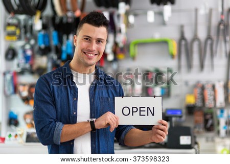 Bike shop owner holding open sign
