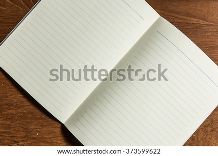 Open blanked notebook on office wood table background.