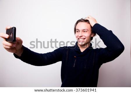 Selfie time! Happy young man taking self portrait photography through smart phone over white background.