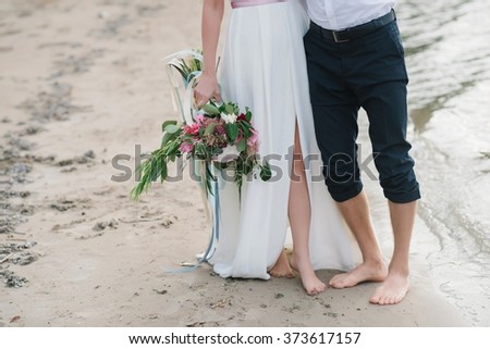 Legs pretty strong young loving couple on the beach over the river, next to a bouquet, lifestyle, concept, love, tenderness
