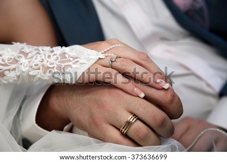 bride and groom show their hands wearing wedding rings
