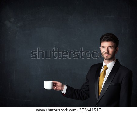 Businessman standing and holding a white cup on a black background 