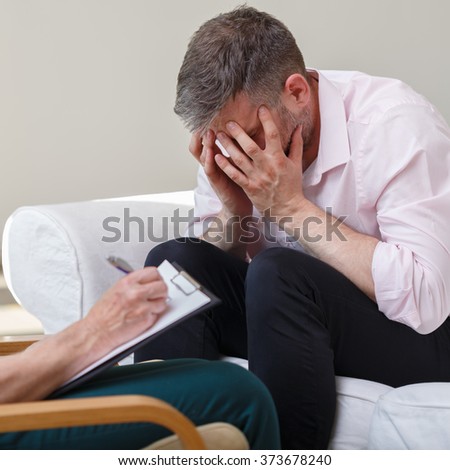 Photo of despair young male with female therapist