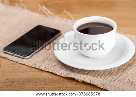 High angle view of smart phone with blank screen and espresso coffee cup on wooden surface