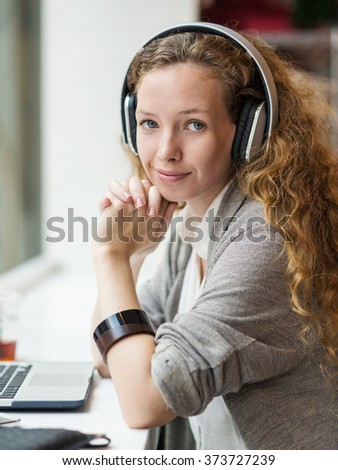 Businesswoman portrait while working with her laptop and listening to music inside a bar. 