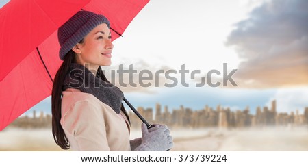 Smiling brunette holding red umbrella against path in yellow field leading to city