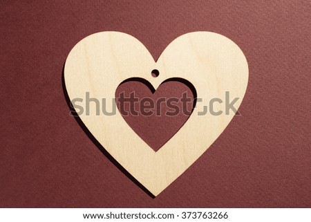 Wooden heart placed on maroon background