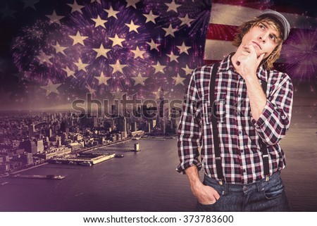 Focused hipster man thinking against composite image of colourful fireworks exploding on black background