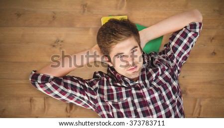 Hipster with hands behind head lying on hardwood floor against bleached wooden planks background