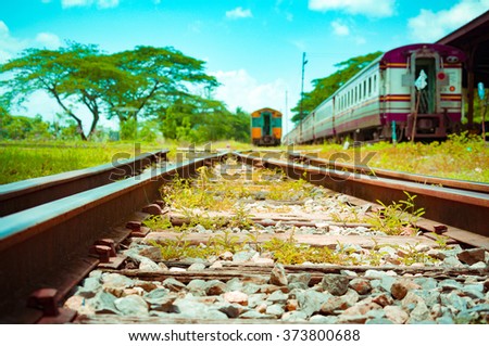 A shot looking down the tracks from train platform. Beautiful photo of low speed vintage tro commuter train.train station with a train about to leave.