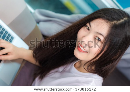 Happy smiling asian women browsing internet on laptop in the bedroom