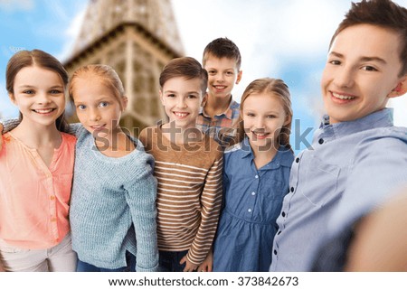 childhood, travel, tourism, technology and people concept - happy children talking selfie over paris eiffel tower background