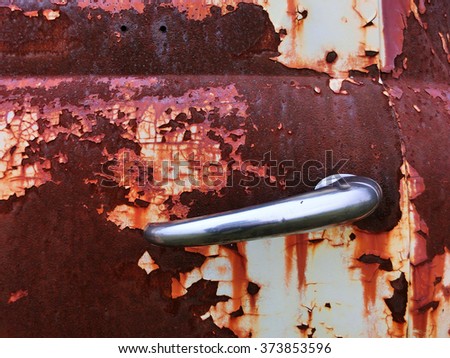 Shiny chrome handle on rusty metal car door - landscape photo