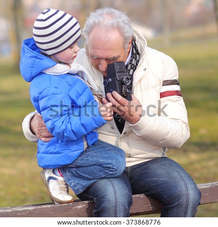 Grandfather with his grandson studying vintage medium format camera. Grandfather shows grandson retro camera