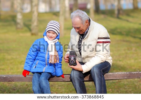 Grandfather with his grandson studying vintage medium format camera. Grandfather shows grandson retro camera