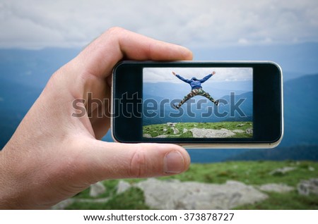 man jumping on top of the mountain, joy, jump, won the top, phone in hand man (photographing the landscape) photographing on the phone, a tourist at the mountain fog. joyful jump