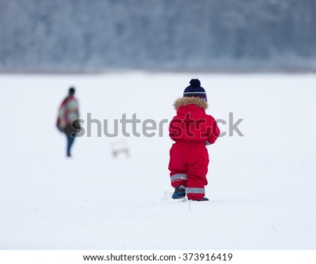 Small boy playing outdoor in snowy winter landscape.