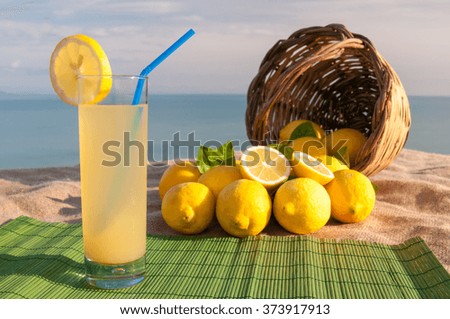 Fresh lemon juice and a full wicker basket on a piece of jute with blue sea in the background
