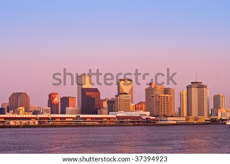 Cityscape of New Orleans CBD from across Mississippi River; buildings lit by sunrise