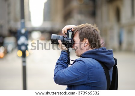 Middle age photographer taking photo with professional digital camera outdoors