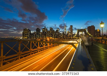 New York view at dusk, with traffic trails on Brooklyn Bridge and Manhattan skyline on background. Travel and transportation concepts on this postcard style picture.