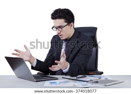 Picture of a shocked middle eastern businessman looking at the laptop screen on the table, isolated on white background