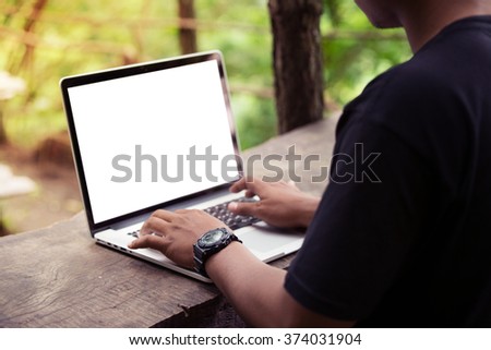 A man is working using laptop at park / outdoor, blank screen for background