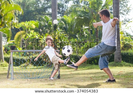 Father and son playing in the park  at the day time. Concept of friendly family. Picture made on the green meadow.