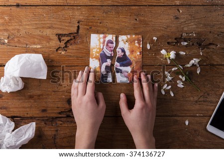 Unrecognizable sad woman holding torn picture of couple in love.  Royalty-Free Stock Photo #374136727