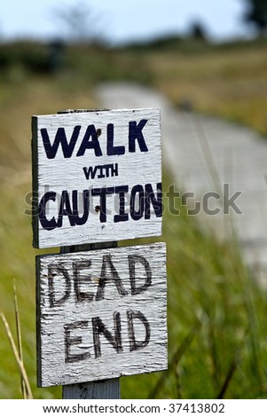 A hand painted sign warning of an unsafe walk that is also a dead end