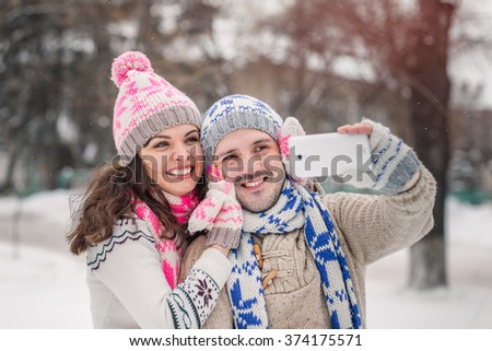 couple in love smiling and making selfie in winter outdoors