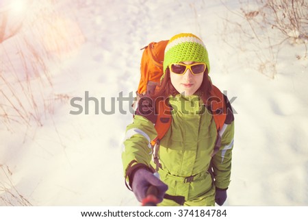 The girl with the backpack is making a selfie during winter walks.

