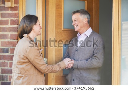Woman Checking On Elderly Male Neighbor Royalty-Free Stock Photo #374195662