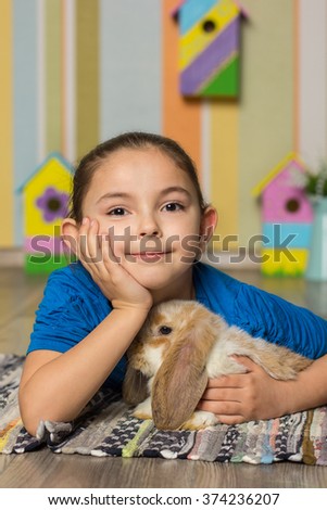 Easter photo. Cute girl sitting on chair with rabbit