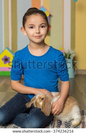 Easter photo. Cute girl sitting on chair with rabbit
