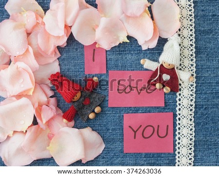 Valentine's day  background. Denim blue background with knitted loving couple man and woman, soft pink rose petals and lettering I love you. Valentine, greeting card. Handmade concept.