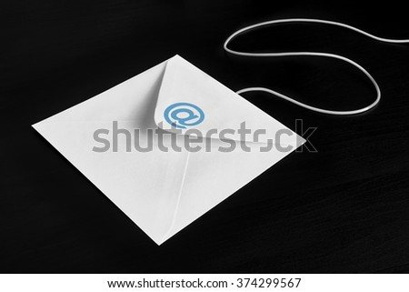 Envelope on black wood table with at Symbol, concept of E-Mail