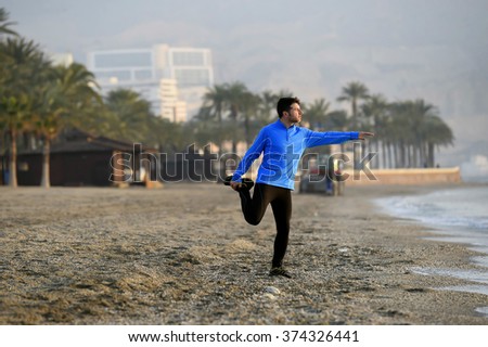 young sport man stretching workout before running on the beach in front of  the sea early morning with mountain background in exercise training and healthy lifestyle concept