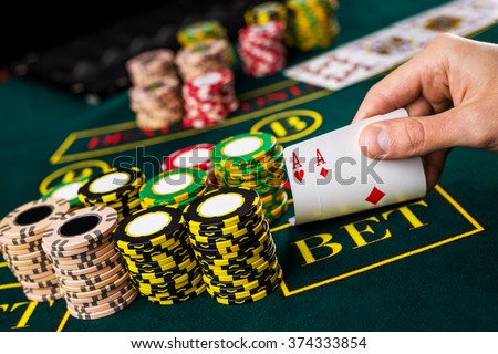 Male poker player lifting the corners of two cards aces  Royalty-Free Stock Photo #374333854