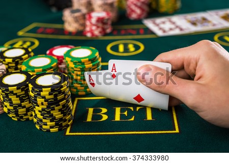 Male poker player lifting the corners of two cards aces  Royalty-Free Stock Photo #374333980
