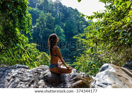 Girl sitting and meditating in forest on top of mountain