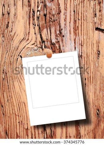 Close-up of one blank square instant photo frame with pin on weathered wood background