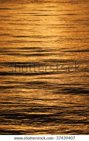 Golden sea background with reflections on the waves at sunset