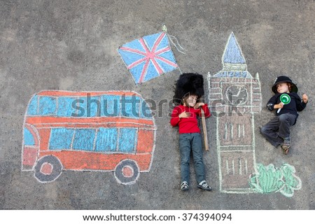 Two funny little friends boys in british queen's guard soldier and policeman uniform having fun with London picture drawing with colorful chalks. With Big Ben, Union Jack and red bus. 