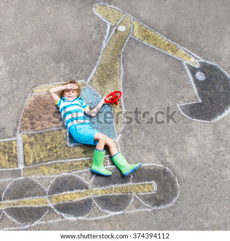 Happy funny little kid boy having fun with excavator picture drawing with colorful chalk. Creative leisure for children outdoors in summer.